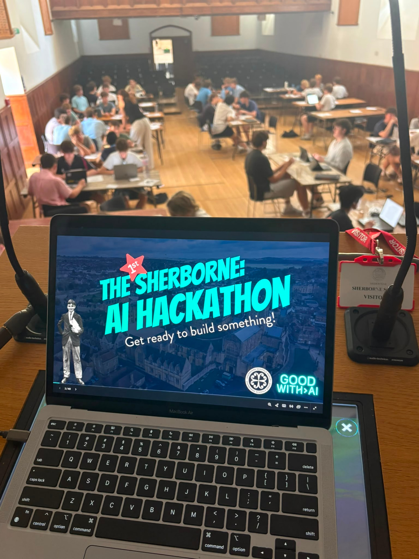 AI hackathon teams working around tables in a school hall, photographed from above